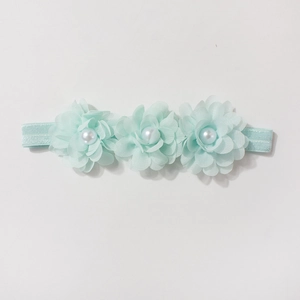 Détail du bandeau bébé vert menthe avec fleurs en mousseline et perles blanches