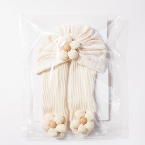 Detailed macro view of infant knit hat and socks set with 3D floral accents in packaging