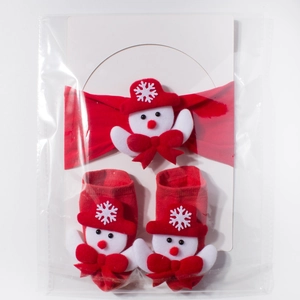 Close-up of baby Christmas gift set with red headband and socks featuring plush snowman
