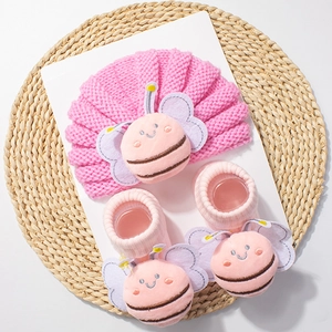 Close-up of pink knit baby hat and socks set featuring 3D plush bee decorations