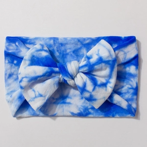 Detail of soft tie-dye nylon baby headband with a large bow in blue and white colors