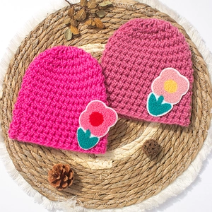 Knitted winter beanies for babies featuring 3D floral accents on a textured woven background