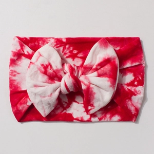 Detailed view of red and white tie-dye elastic baby headband with large bow decoration