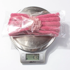 Dettaglio ravvicinato di una fascia rosa lavorata a maglia per neonati, peso di 27,3 g