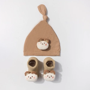 Close-up of baby knit hat and socks set with 3D plush bear head details in khaki