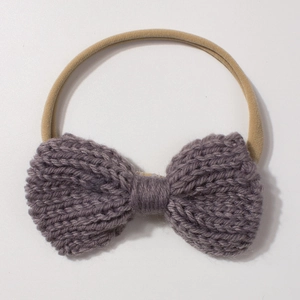 Macro detail of hand-knitted purple bow on soft elastic headband for infants