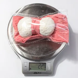 Detailed view of 22.7g baby headband with pink floral bow on a digital scale