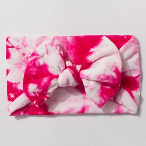 Close-up of soft nylon tie-dye bow headband with vibrant rose red and white patterns