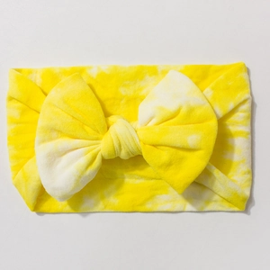 Detail view of yellow tie-dye baby headband featuring a large elastic knot bow detail