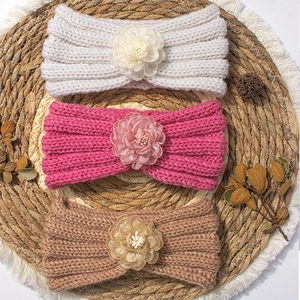 Tre fasce per neonati a maglia con fiori di tulle su sfondo rustico accogliente