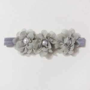 Détail du bandeau bébé avec trois fleurs en mousseline grise et perles centrales