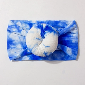 Detail view of blue and white tie-dye wide nylon baby headband with donut-shaped knot