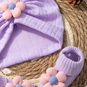 Detail of lavender knit baby hat and socks set featuring delicate 3D floral accents