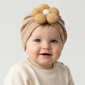 Detail of light brown infant hat with herringbone knit texture and corduroy flower