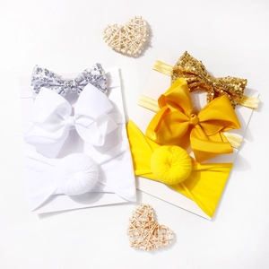 Close-up of baby headbands with sequin bows and ribbed silk knots on white cards