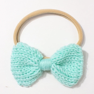 Detailed close-up of handmade knit mint green bow on a soft elastic nylon baby headband