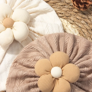 Detail of cream and brown baby knitted hats with textured ribbing and 3D flower accents