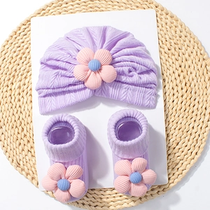 Detail of soft purple knit baby turban hat and matching socks with 3D floral accents