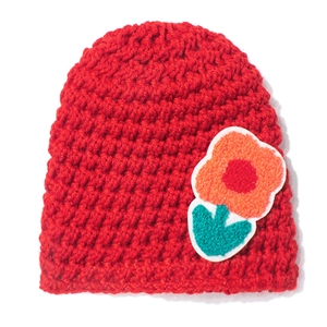 Detail of red crochet baby beanie featuring a colorful textured flower applique patch