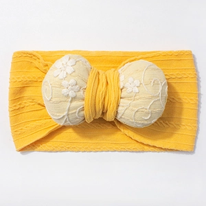 Detail of baby yellow jacquard headband with embroidered flower bow and cable knit texture