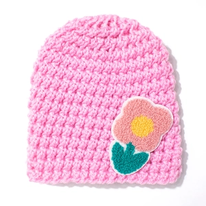 Close-up of bright pink knitted baby hat featuring soft flower embroidery detail