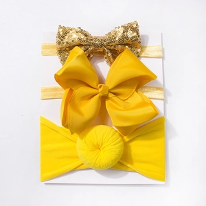 Three-piece baby headband set featuring yellow ribbed bows and gold sequins on a display card