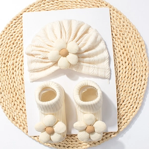 Creamy white baby set with waffle knit hat and floral socks on straw mat decoration
