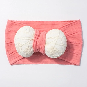 Detailed view of pink knitted baby headband with a white lace floral embroidered bow