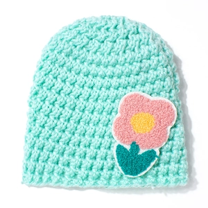 Close-up of mint green knitted baby hat featuring 3D pink flower embroidery detail