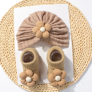 Detail of baby turban hat and socks set with 3D floral accents in warm beige cotton