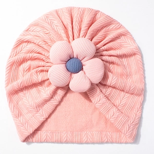 Pink knit baby turban hat with a large decorative five-petal flower and a blue center