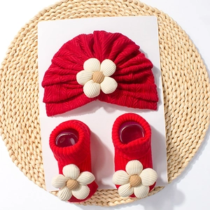 Detail view of red baby turban hat and matching socks with white 3D floral accents
