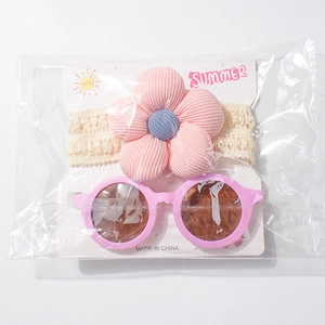 Detailansicht der rosa Baby-Sonnenbrille und des Spitzen-Stirnbandes in Verpackung