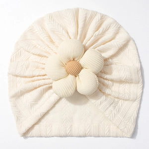 Detail of cream rib-knit baby turban featuring a large 3D flower and soft texture