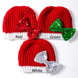Detail of Christmas baby knit hats featuring large sequin bows in red, green, and white