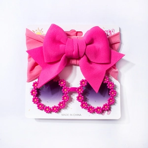 Detail of rose red bow headband and pink daisy sunglasses set for baby girls