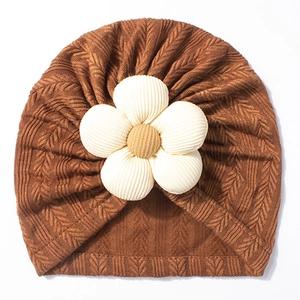 Detailed close-up of a brown knit baby turban with a 3D floral decoration