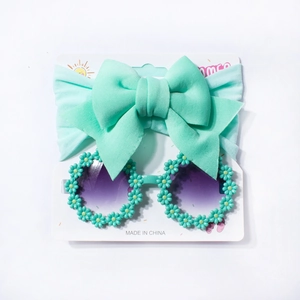 Mint green baby headband with large bow and matching daisy sunglasses set on display card