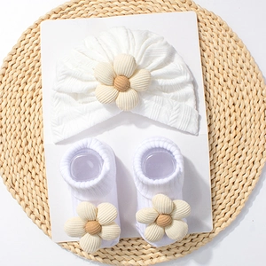 Detailed view of white knit baby hat and socks set featuring fabric floral decorations