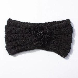 Dettaglio fascia neonato in maglia nera con fiore in tessuto 3D e perla centrale