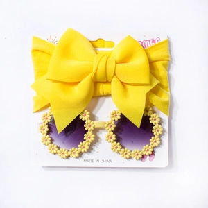 Detail view of baby yellow bow headband and round sunflower daisy sunglasses set