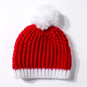 Close-up of red and white knit baby winter hat featuring a fluffy white pom-pom detail