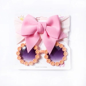 Detail of pink bow headband and round sunglasses with daisy flower petals for infants