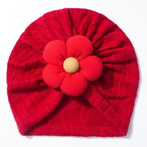 Close-up of baby knit hat showing arrow pattern texture and 3D floral decoration
