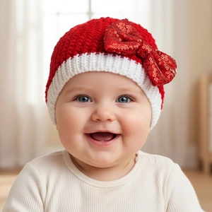 Detail of baby knit hat featuring a large red sequin bow and white ribbed trim edges