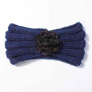 Dettaglio della fascia in maglia blu scuro per neonato con fiore nero e trama di lana