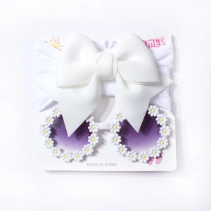 Macro shot of baby summer set with white bow headband and daisy sunglasses on card