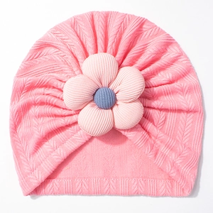 Detail of pink baby knit turban hat featuring a large 3D flower and soft braided texture