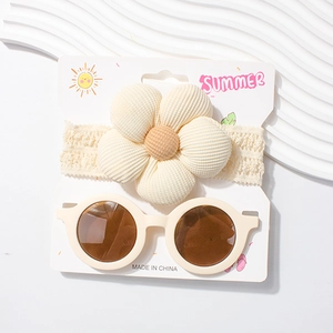 Detail von Baby-Spitzenstirnband und runder Retro-Sonnenbrille auf einer Displaykarte