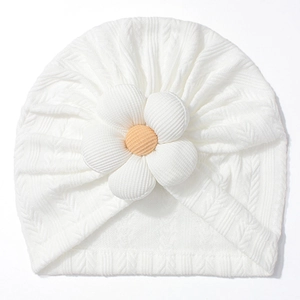Close-up of white cable knit baby hat featuring a 3D yellow sunflower embellishment